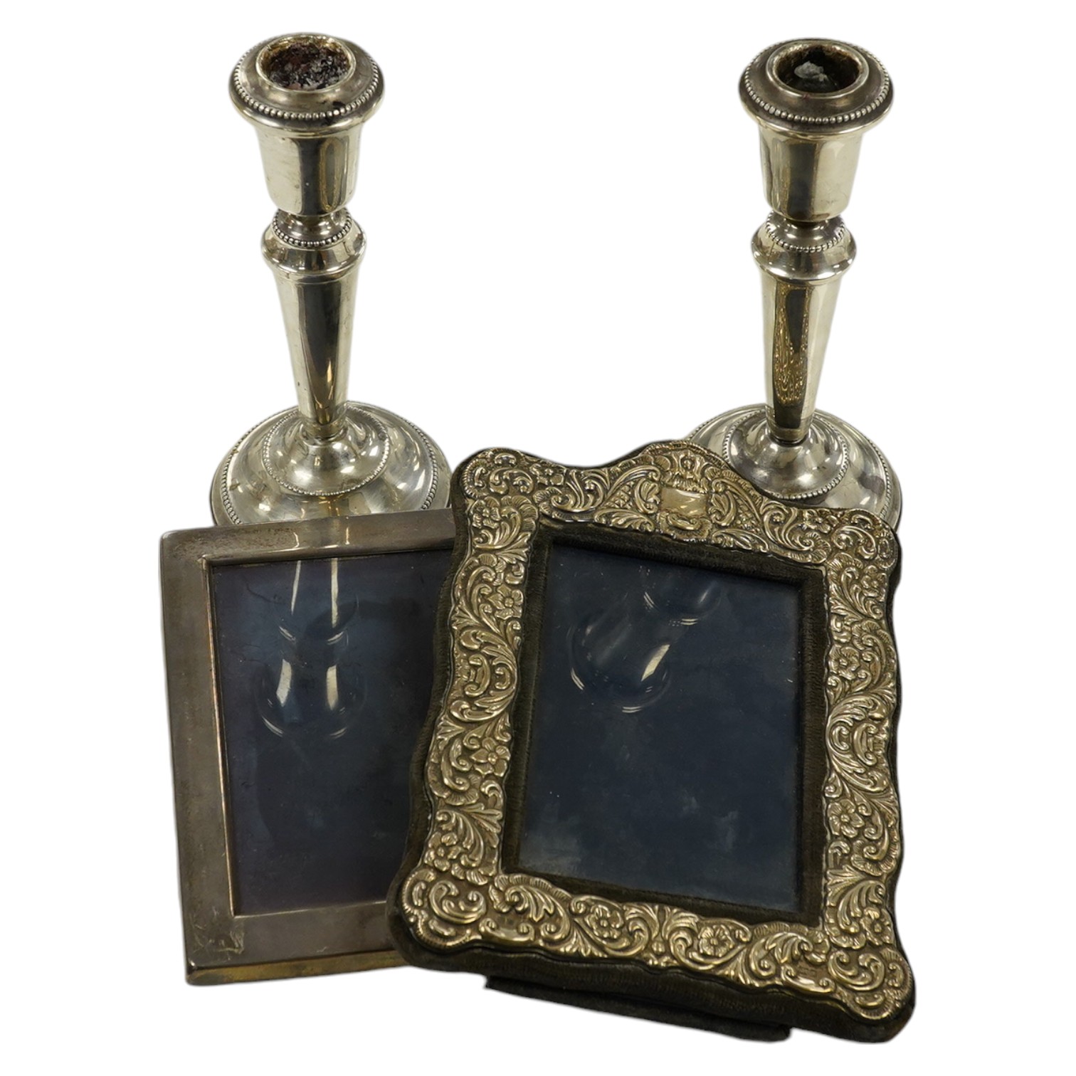 A pair of modern loaded silver candlesticks, 18cm high, an embossed silver mounted photograph frame, 20cm and a plain rectangular photograph frame, 16cm. Condition - fair to good